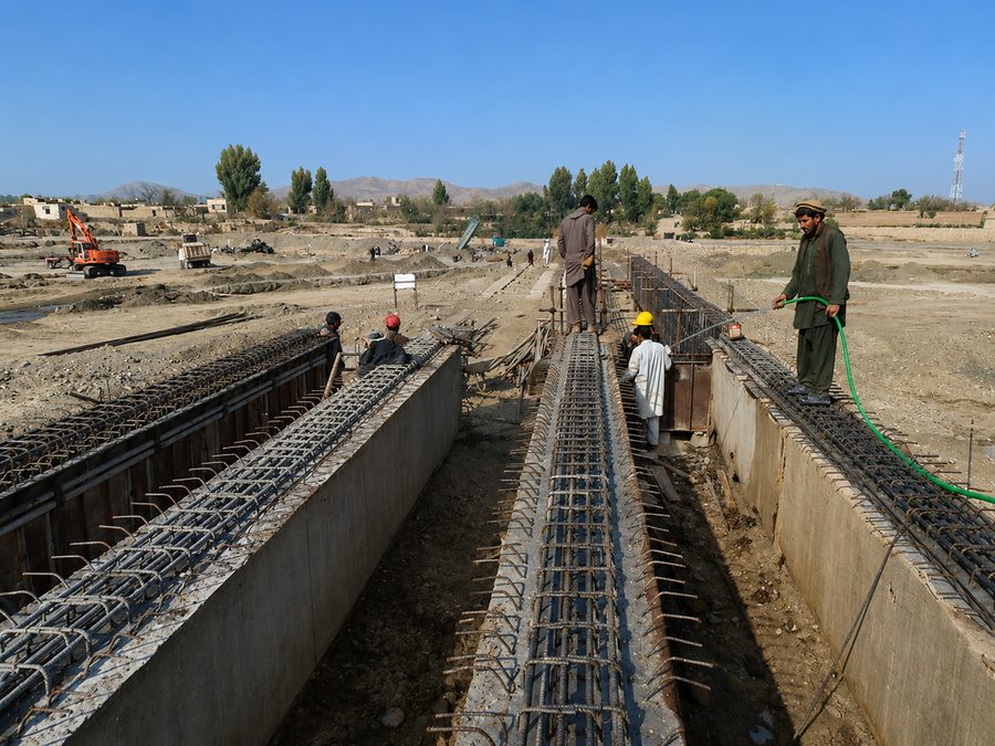 Reinforcement cages and formwork for the deck and abutment walls of the 120 metre RCC bridge at Shahr-e-Kohna Nahrin under construction, with workers curing the concrete on the Khost-e-Firang road in Baghlan province