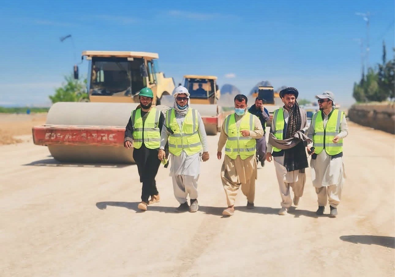 Engr. Azizullah Niazi, President of MECC, walking the alignment of the Chawk Dand to Bagh Pol road in Kandahar province with site staff, with a soil compactor working behind them